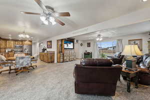 Carpeted living room with ceiling fan with notable chandelier