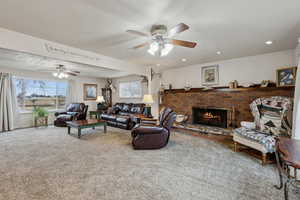 Living room with ceiling fan, carpet floors, and a brick fireplace