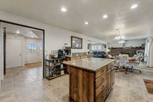 Kitchen with ceiling fan, a kitchen island, and light stone countertops