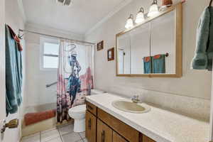 Full bathroom with vanity, tile patterned floors, shower / bathtub combination with curtain, and ornamental molding