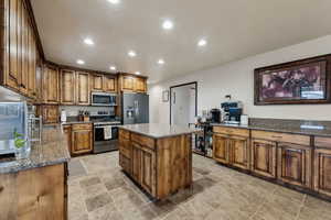 Kitchen featuring dark stone countertops, sink, a center island, and appliances with stainless steel finishes