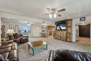 Living room with a barn door, ceiling fan, and carpet