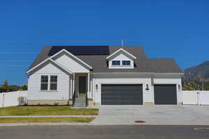 View of front of house featuring a front yard, solar panels, and a garage