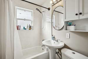 Full bathroom featuring sink, shower / tub combo with curtain, and toilet