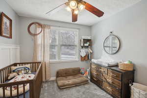 Carpeted bedroom with ceiling fan, a textured ceiling, and multiple windows