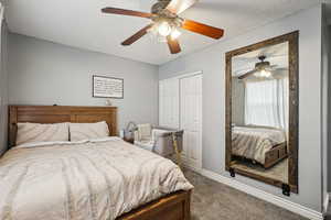 Carpeted bedroom with ceiling fan and a closet