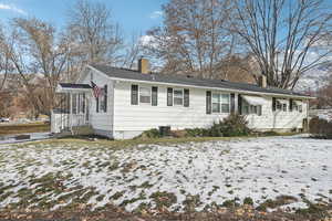 Snow covered rear of property featuring cooling unit