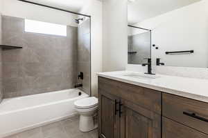 Full bathroom featuring tile patterned floors, toilet, vanity, and tiled shower / bath