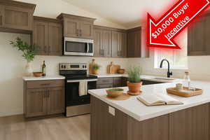 Kitchen with appliances with stainless steel finishes, a sink, lofted ceiling, light countertops, and light wood finished floors