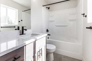 Full bathroom featuring washtub / shower combination, vanity, toilet, and tile patterned flooring