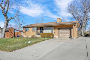 Ranch-style house with a garage and a front lawn