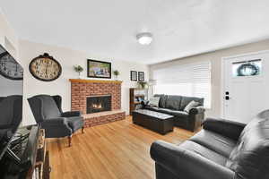 Living room with a fireplace, wood-type flooring, and a textured ceiling