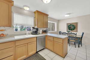 Kitchen featuring a wealth of natural light, dishwasher, sink, light brown cabinetry, and light tile patterned floors