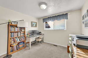 Office space with a textured ceiling and light carpet