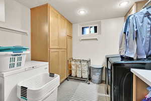 Laundry room with cabinets, a textured ceiling, and washing machine and dryer