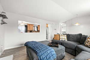 Living room with hardwood / wood-style floors, ceiling fan, and vaulted ceiling