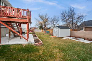 View of yard featuring a wooden deck, a patio, and a shed