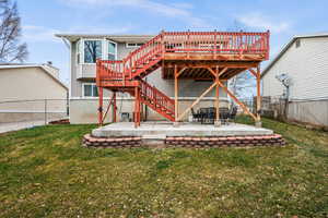 Rear view of property featuring a lawn, a patio area, and a deck