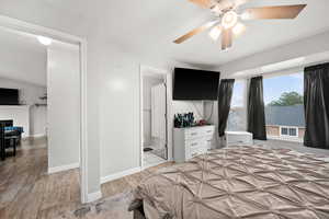 Bedroom featuring ceiling fan, a fireplace, light hardwood / wood-style floors, and lofted ceiling