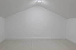 Bonus room featuring light colored carpet and vaulted ceiling