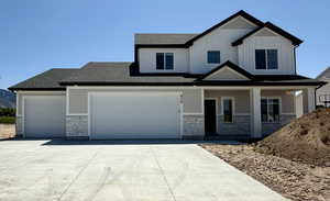 View of front of home with stone siding, concrete driveway, covered porch, board and batten siding, and roof with shingles