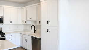 Kitchen featuring white cabinets, sink, appliances with stainless steel finishes, and light hardwood / wood-style flooring