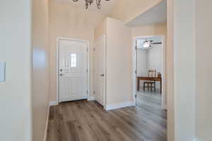 Entryway with light wood-type flooring and an inviting chandelier