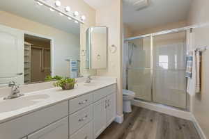 Bathroom featuring vanity, toilet, a shower with door, and wood-type flooring