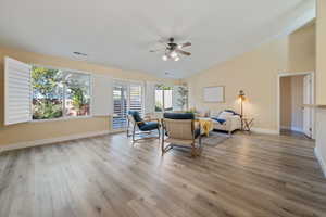 Living room with ceiling fan, light hardwood / wood-style floors, and lofted ceiling