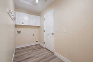 Clothes washing area featuring hookup for an electric dryer, cabinets, hookup for a washing machine, and light hardwood / wood-style floors