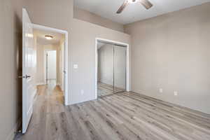 Unfurnished bedroom with a closet, ceiling fan, and light wood-type flooring