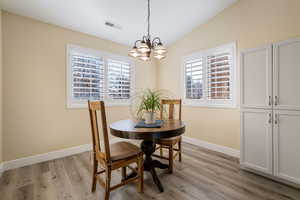 Dining area featuring an inviting chandelier, light hardwood / wood-style flooring, and vaulted ceiling