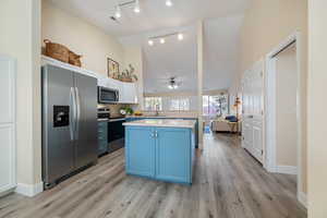 Kitchen featuring white cabinets, appliances with stainless steel finishes, sink, light hardwood / wood-style flooring, and blue cabinets