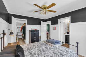 Bedroom with ensuite bath, ceiling fan, crown molding, a spacious closet, and a closet