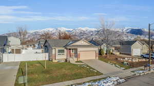 Ranch-style house featuring a mountain view, a front lawn, and a garage