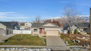 Single story home with a mountain view, a front yard, and a garage