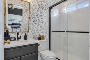 Bathroom featuring vanity, toilet, walk in shower, and ceiling fan