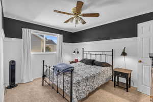 Carpeted bedroom featuring ceiling fan and crown molding