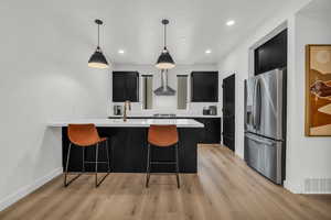 Kitchen featuring sink, wall chimney exhaust hood, decorative backsplash, decorative light fixtures, and stainless steel appliances