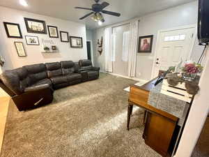 Carpeted living room with ceiling fan