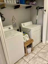 Clothes washing area with separate washer and dryer and light tile patterned floors