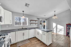 Kitchen featuring white cabinetry, white appliances, and hanging light fixtures