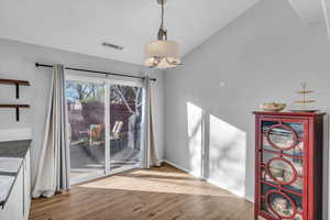 Dining room with light hardwood / wood-style floors and vaulted ceiling