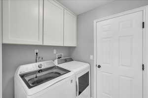 Washroom with washing machine and clothes dryer and cabinets