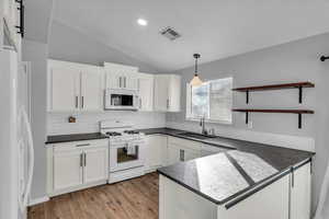 Kitchen featuring white appliances, white cabinets, sink, decorative backsplash, and decorative light fixtures