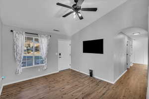 Unfurnished living room featuring hardwood / wood-style floors, vaulted ceiling, and ceiling fan