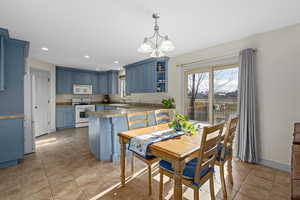 Dining area featuring a chandelier and tile flooring. Shows kitchen. Fridge is included.