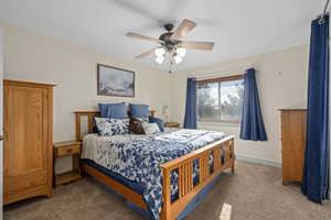 Primary Bedroom with double door entry, carpet, and ceiling fan