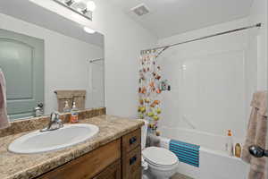 Full bathroom featuring shower / tub combo with curtain, vanity, and toilet