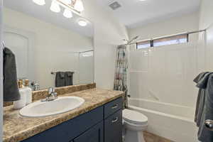 Full bathroom with tile floors, shower / tub combo with curtain, vanity, and toilet